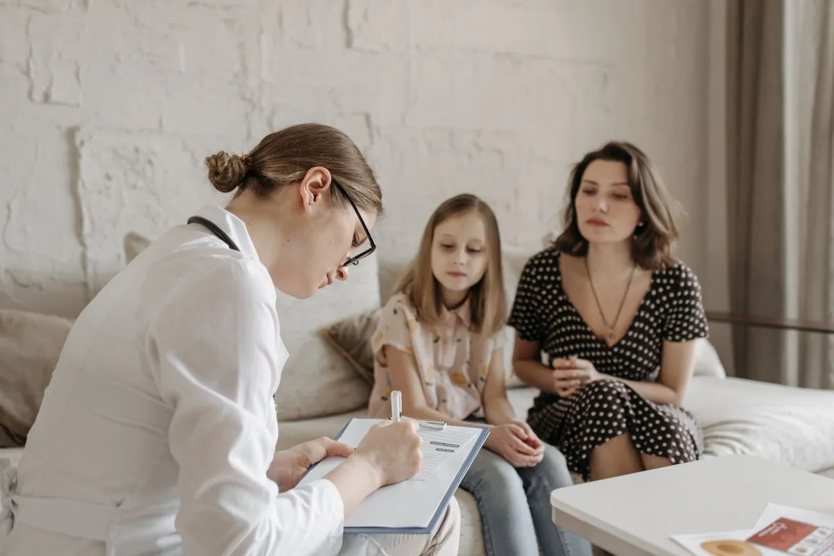 A pediatrician reviews care notes with a mother and her daughter